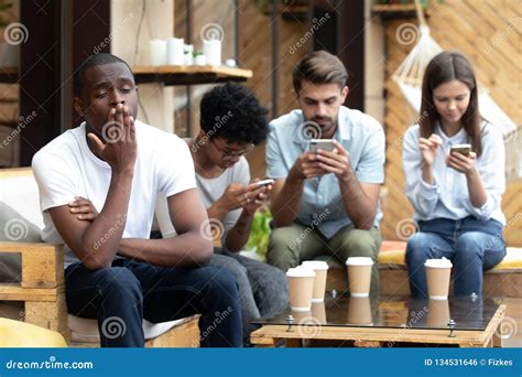 Bored African American Man Sitting With People With Phone Depend Stock