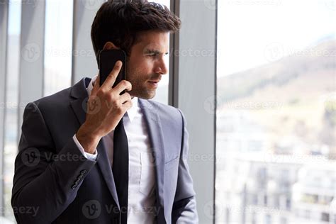 Businessman Making Phone Call Standing By Office Window 1177328 Stock