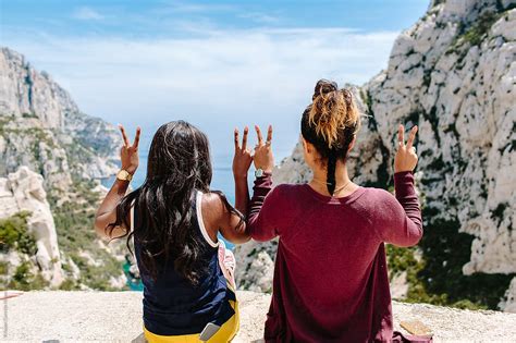 Two Best Friends Holding Up The Peace Sign While They Look Down