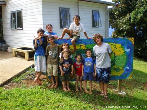 A Group Of Young Children Standing In Front Of A House With A Blue And