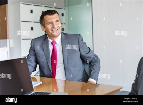 Happy Mature Businessman Sitting At Desk In Office Stock Photo Alamy