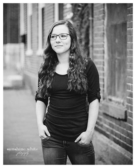 A Black And White Photo Of A Woman Standing In Front Of A Brick