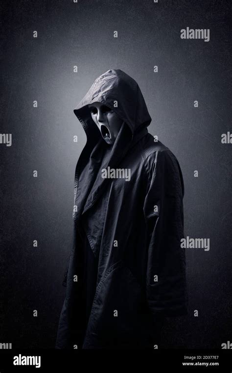 Scary figure with mask in hooded cloak in the dark Stock Photo - Alamy