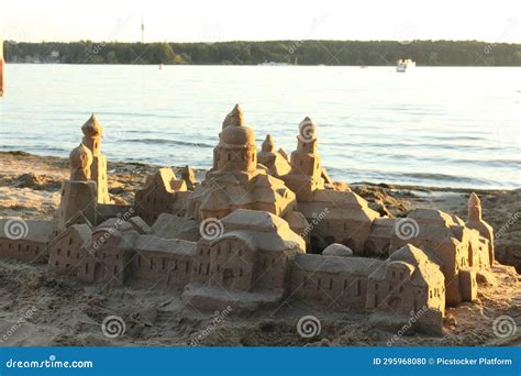 A Sand Castle On A Beach With A Body Of Water In The Background Stock