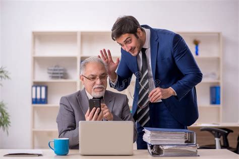 Jefe Masculino Viejo Y Empleado Joven En La Oficina Foto De Archivo