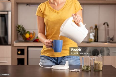 Woman Pouring Boiling Water From A Kettle Into A Tea Cup Stock Photo