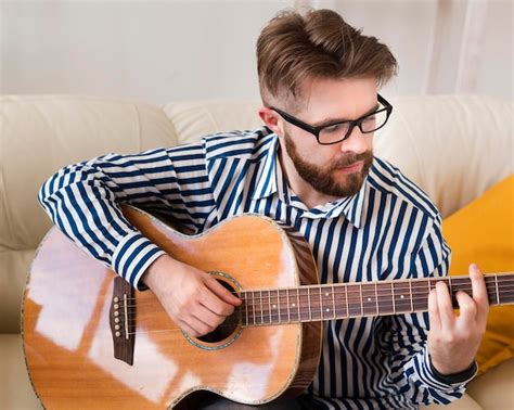 Uomo Che Suona La Chitarra A Casa Sul Divano Foto Gratis