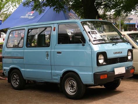 A Small Blue Van Parked Next To A White Car