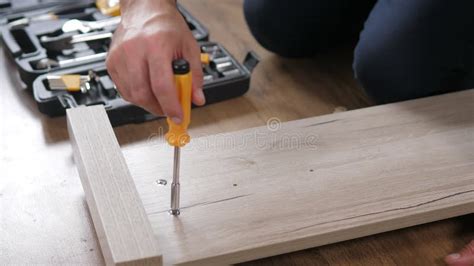 Close Up Of A Man S Hands Assembling A Wooden Bed Using A Screwdriver