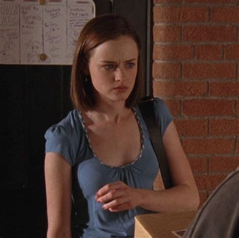 A Woman Sitting At A Table In Front Of A Brick Wall