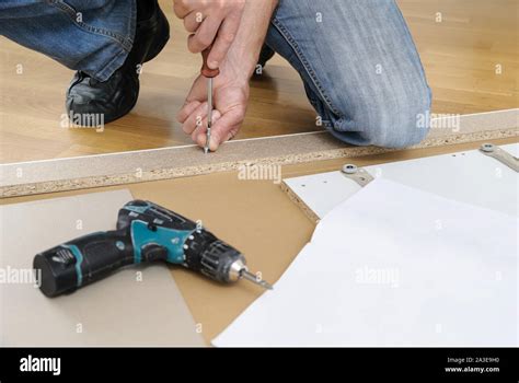 A Man Is Assembling The Furniture At Home He Is Installing Joint