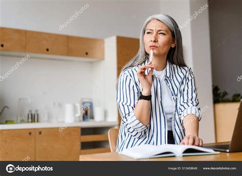 Serious White Haired Mature Woman Writing Notes Working Laptop Indoors Stock Photo