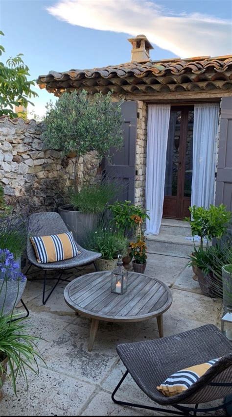 An Outdoor Patio With Chairs Table And Potted Plants