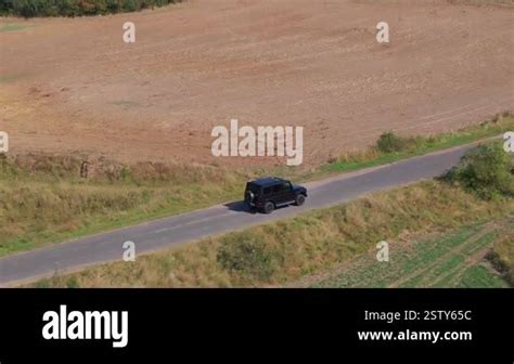 Aerial Perspectives Reveal A Black Suv Cruising Along A Rural Road