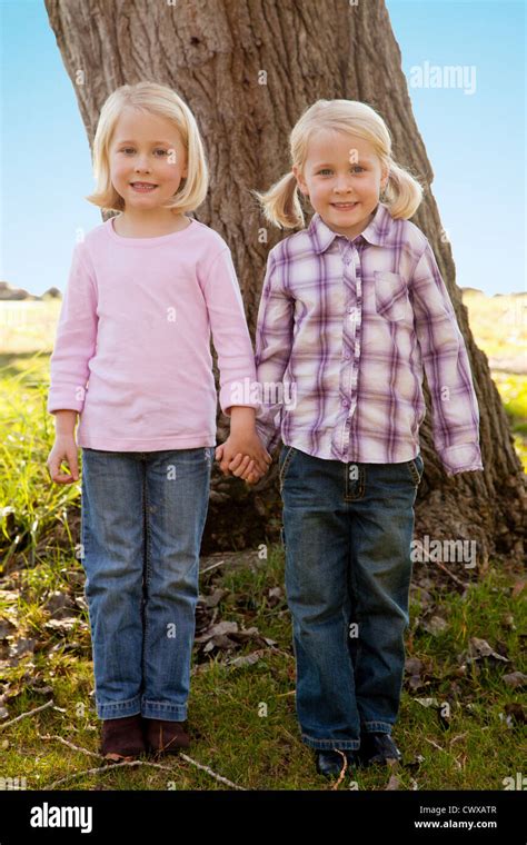 Zwei blonde Mädchen stehen neben einander vor einen Baum Stockfotografie Alamy