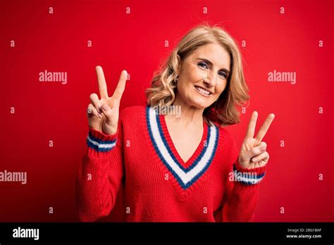 Middle Age Beautiful Blonde Woman Wearing Casual Sweater Over Isolated Red Background Smiling
