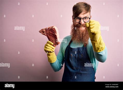 Redhead Irish Butcher Man With Beard Holding Raw Beef Steak Over Pink