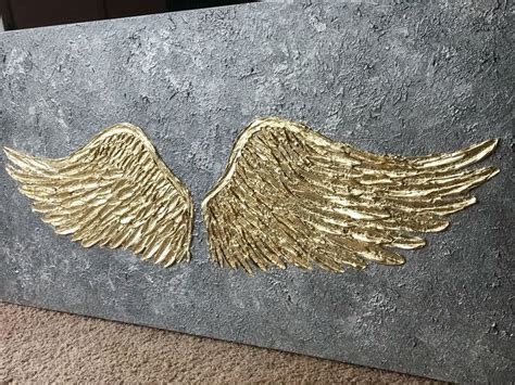 gold angel wings painted on a gray wall