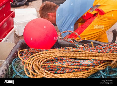 Two Fishermen Prepare Their Nets Before Heading Out To Sea From Lyme