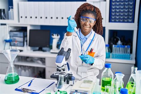 African American Woman Scientist Pouring Liquid On Test Tube At