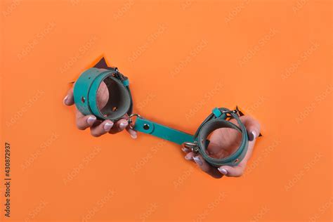 Adult sex toys minimal design isolated on an orange background Women s hands in handcuffs 스톡