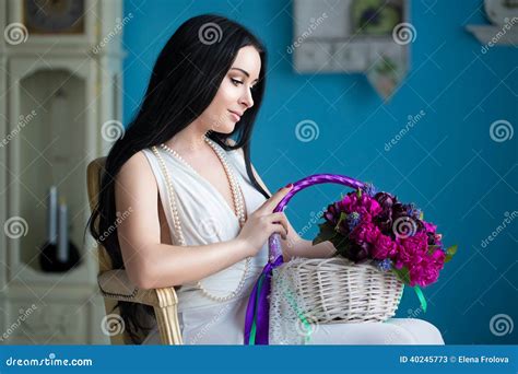 Het Mooie Jonge Brunette In Witte Kleding En Een Parelhalsband Zitten