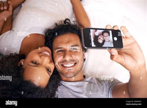 Capturing The Moment A Cute Couple Taking A Selfie On The Bed Stock