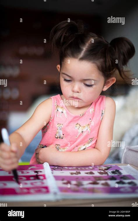 Una niña de cuatro años está coloreando en las letras de un libro