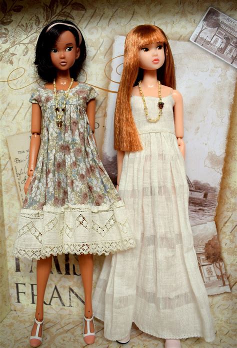 Two Dolls Standing Next To Each Other In Front Of A Wall With Pictures