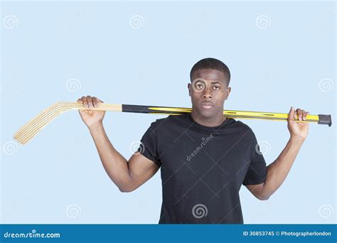 Portrait Of An African American Man Holding Hockey Stick Over Blue