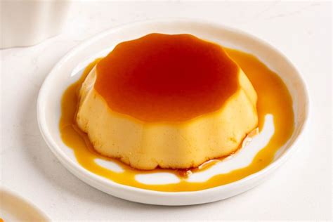 a small white plate topped with a flan covered in caramel sauce on top of a table