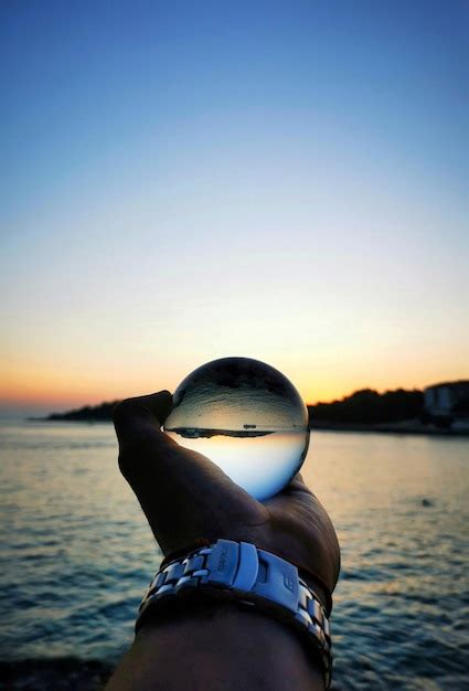 Premium Photo Cropped Hand Of Person Holding Crystal Ball At Sunset