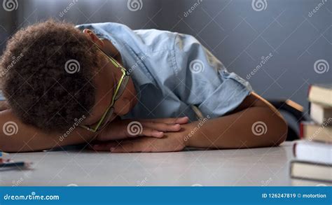 Unmotivated School Boy Sleeping On Library Desk Near Pile Books Boring