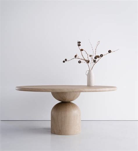 A White Vase With Some Flowers In It On A Wooden Table Next To A Wall