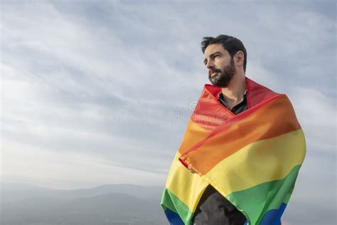 Gay Riendo Sentado Con Una Bandera Gay Mirando El Horizonte Foto De Archivo Imagen De Sentado