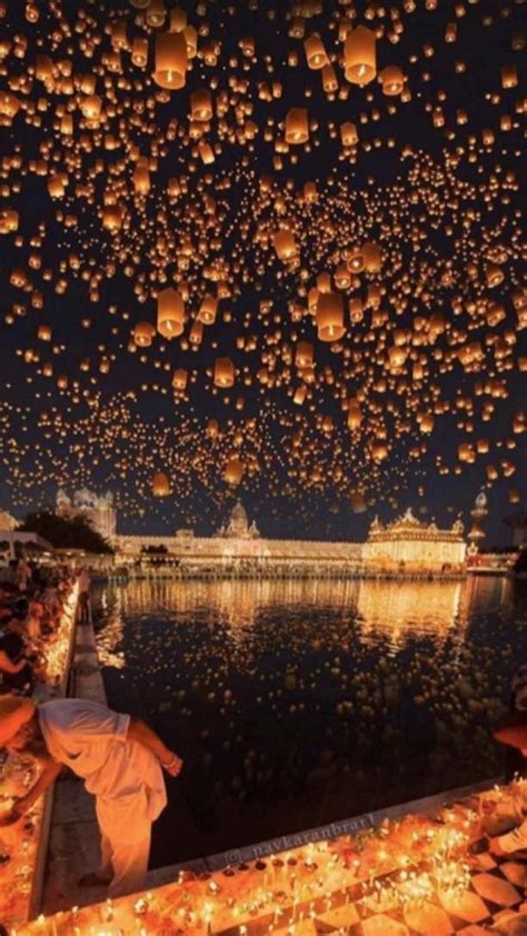 Many Lanterns Floating In The Air Over Water At Night With People