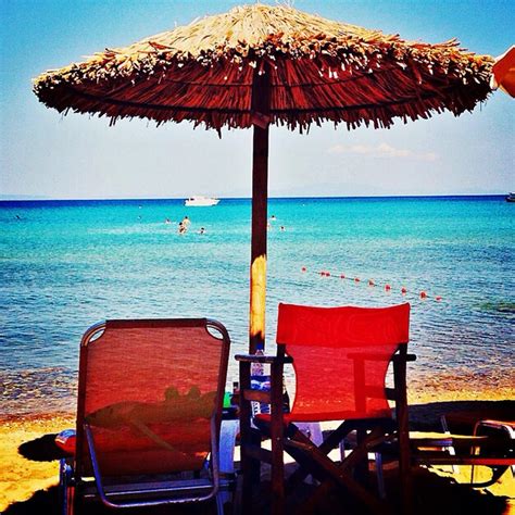 Premium Photo Deck Chairs Under Thatched Parasol On Beach