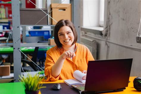 Uma Morena Numa Blusa Laranja Trabalha Num Computador Portátil Na