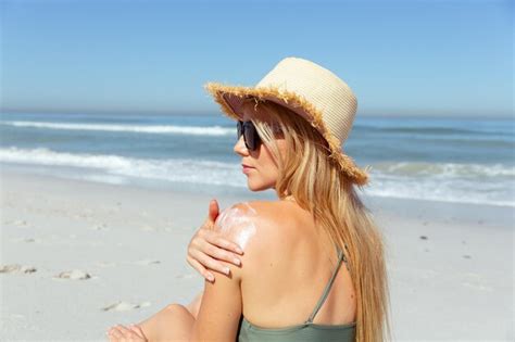 Una mujer caucásica con sombrero disfrutando del tiempo en la playa en