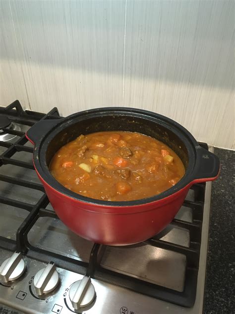 A Red Pot Filled With Soup Sitting On Top Of A Stove