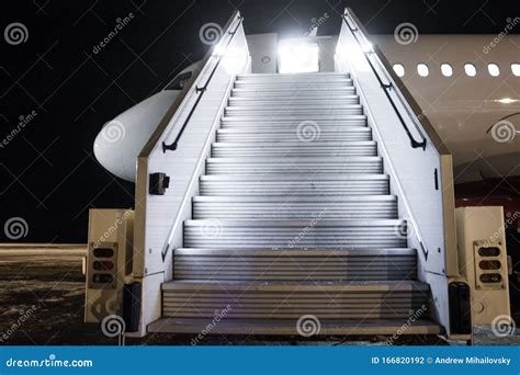 Passenger Aircraft With A Boarding Ramp On The Night Airport Apron