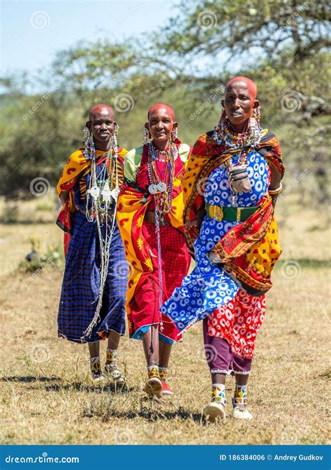 Masai Women In Traditional Clothing Is Walking In The Savannah