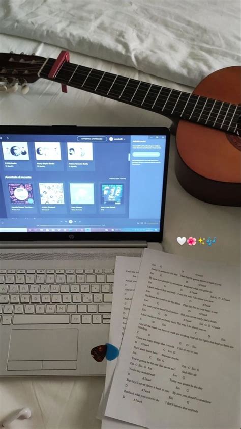 An Open Laptop Computer Sitting On Top Of A Desk Next To A Guitar And Paper