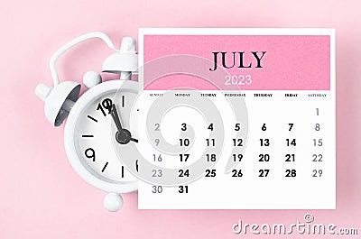 The July 2023 Monthly Calendar Year With Alarm Clock On Pink Colour