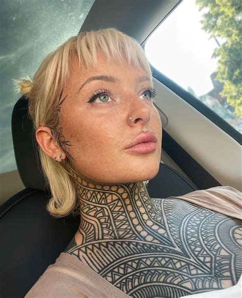 A Woman With Tattoos On Her Neck And Chest Sitting In The Back Seat Of