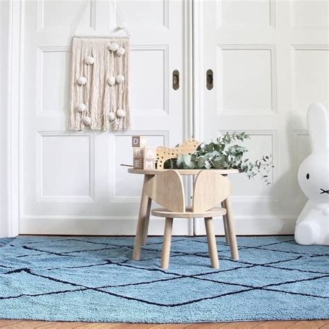 A Wooden Chair Sitting On Top Of A Blue Rug In Front Of A White Door