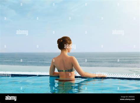 Luxury Resort Woman Relaxing In Infinity Swimming Pool Water