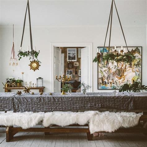 The Dining Room Table Is Decorated With Greenery And Hanging Art On The