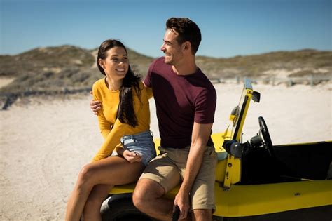 Casal caucasiano feliz sentado no buggy de praia abraçando o mar pausa