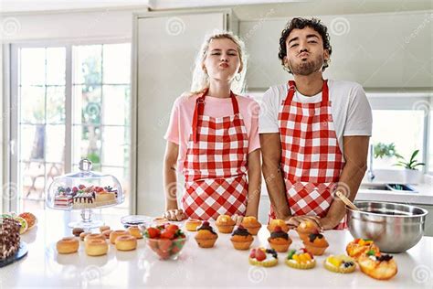 Couple Of Wife And Husband Cooking Pastries At The Kitchen Puffing Cheeks With Funny Face Stock